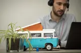 blauwe lego volkswagen busje op bureau met op de achtergrond leaseadviseur daan achter laptop